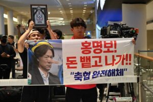 Hong Myung-bo entre manifestantes no Aeroporto de Incheon
