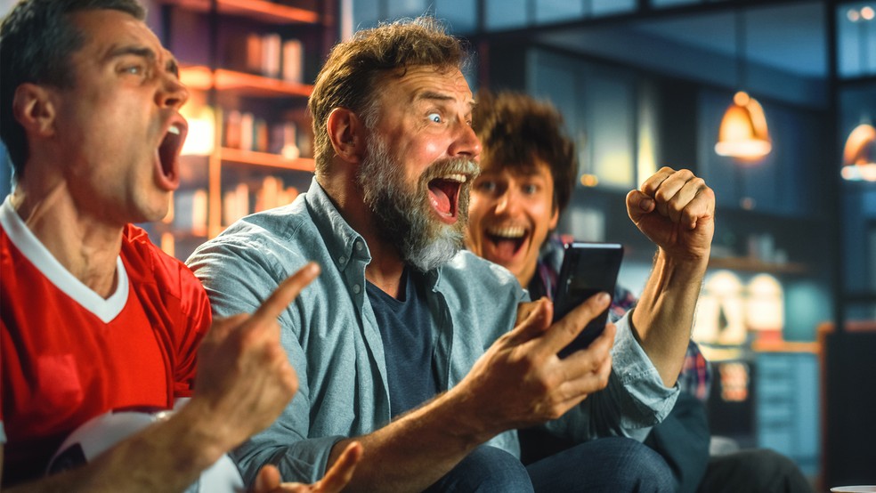 Amigos celebrando em casa durante Encontros da Copa com decoração temática