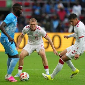 Jogadores de Dinamarca e República Democrática do Congo disputando bola em amistoso em Liege, Bélgica