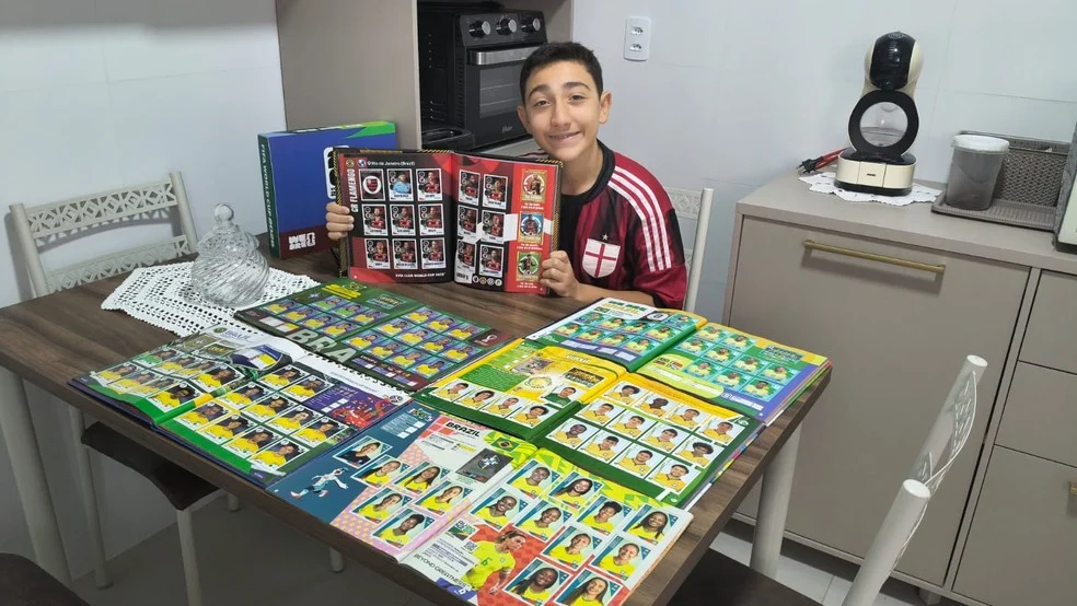 Arthur com o álbum da Copa e as figurinhas