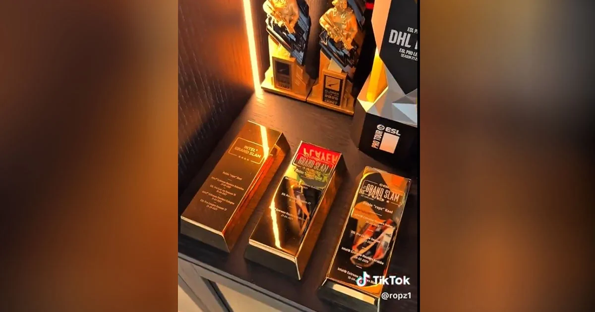 ropz fazendo unboxing barra de ouro do ESL Grand Slam ao lado de troféus